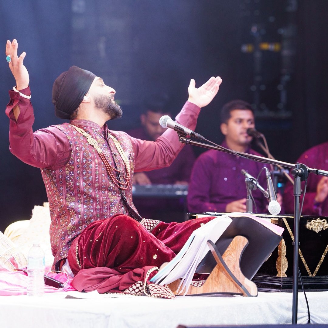 San2 performing live at the harmonium with his arms raised